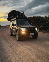 Mitsubishi Pajero on a dirt road with a scenic sky